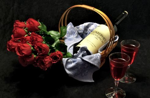 Red roses in a basket with a bottle of wne