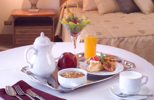 Breakfast laid out on a table in a guestroom with a king sized bed.