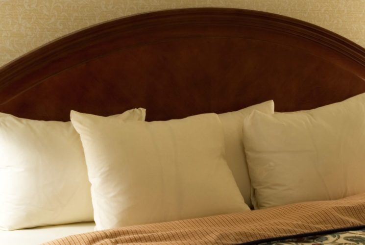 Wooden headboard with several fluffy white pillows