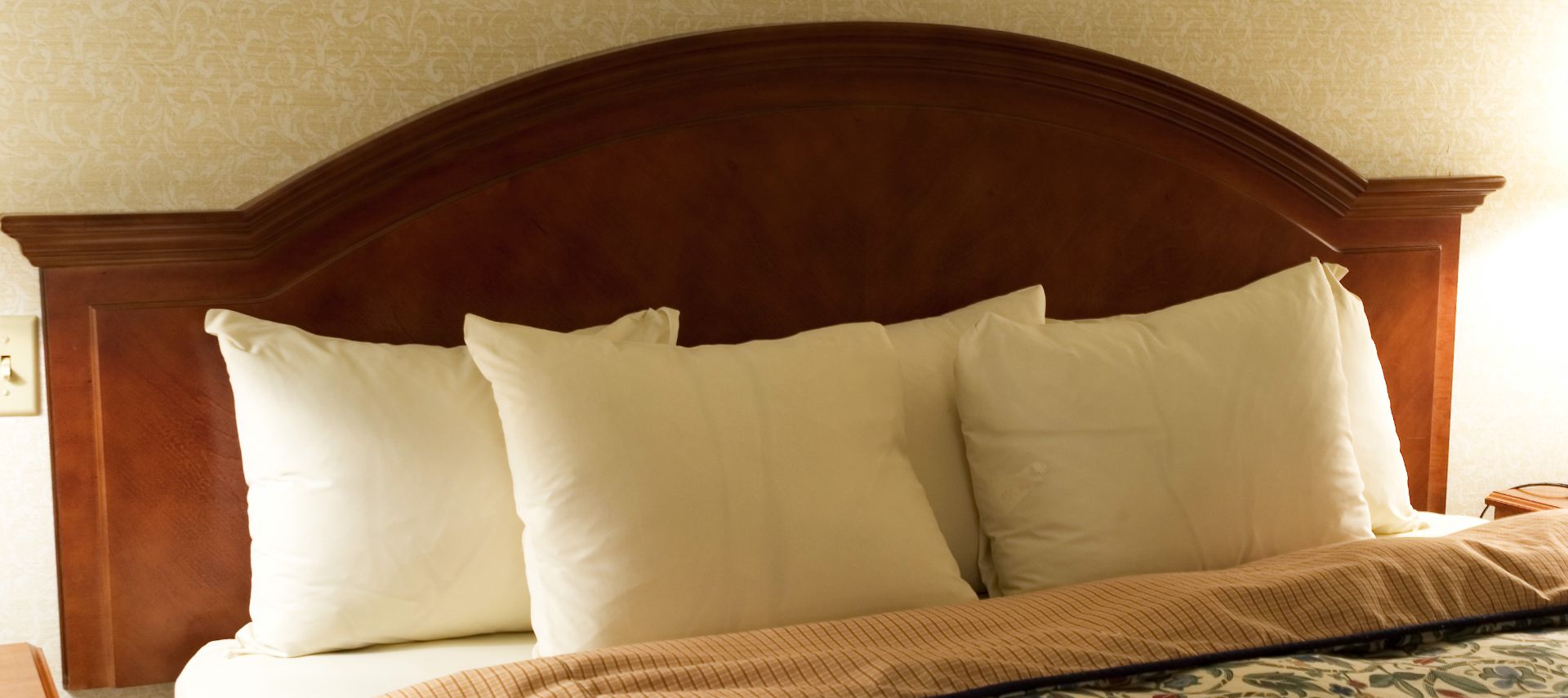 Wooden headboard with several fluffy white pillows